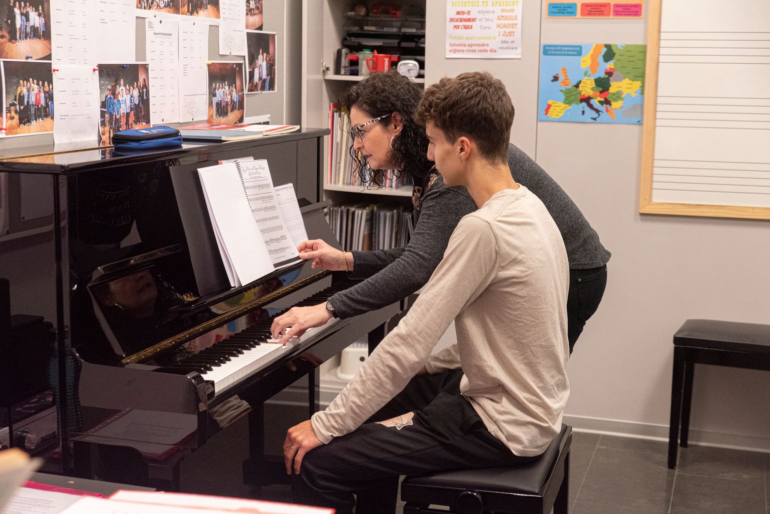 Una professora de piano mira amb el seu alumne les partitures a una classe de l'Escola Municipal de Música de Nou Barris