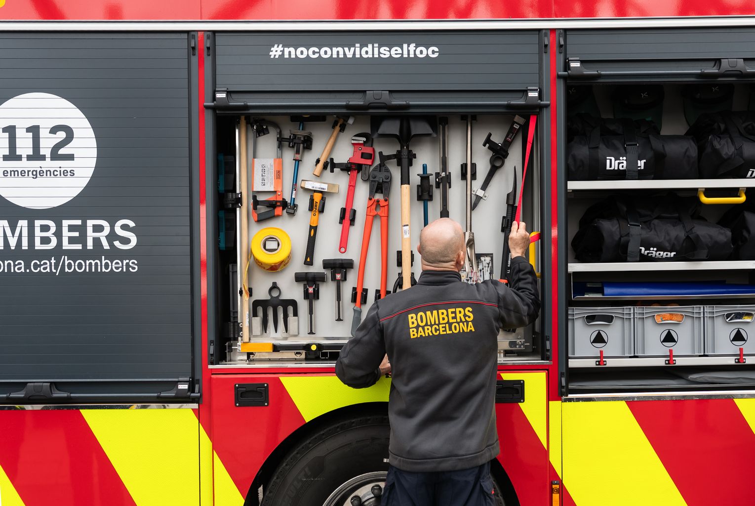 Un bomber d’esquena obre el lloc de les eines dels vehicles nous dels Bombers de Barcelona