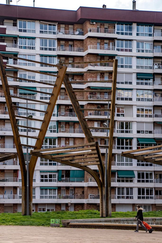 Elements ornamentals de fusta i vidre al parc Central de Nou Barris. Pel seu costat passa una dona amb un carretó de la compra. Districte de Nou Barris. Barri de la Guineueta. 
