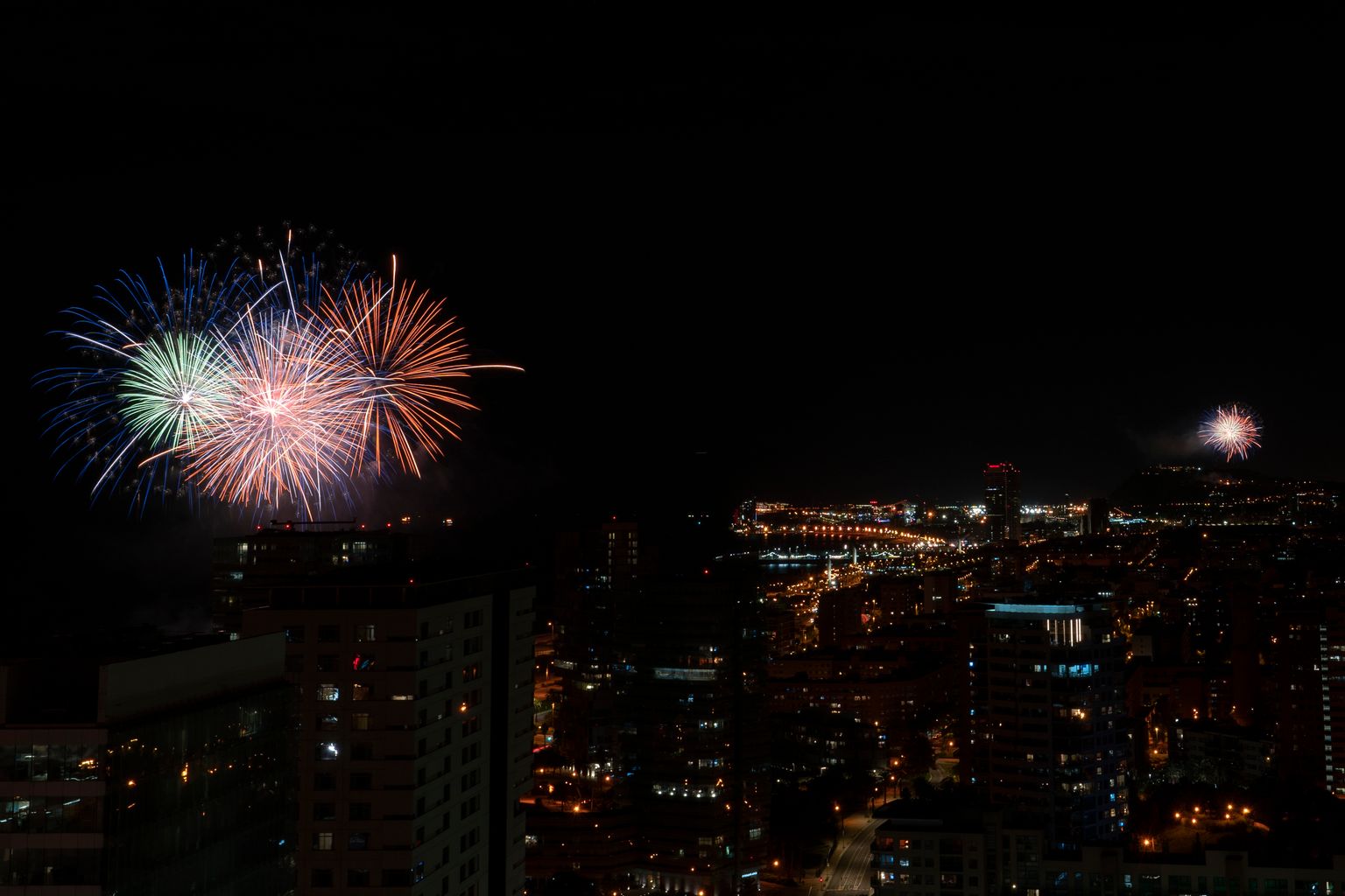 Vistes de la ciutat amb els focs d'artifici del piromusical des de dos punts, l'Espigó de Bac de Roda a Sant Martí i el Castell de Montjuïc, a Sants-Montjuïc