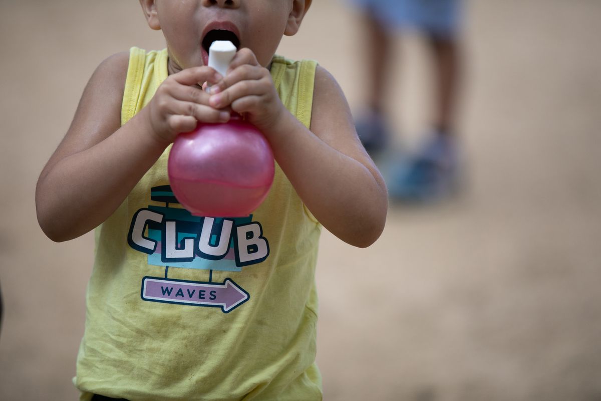 
             Un infant bufa un globus al pati de l