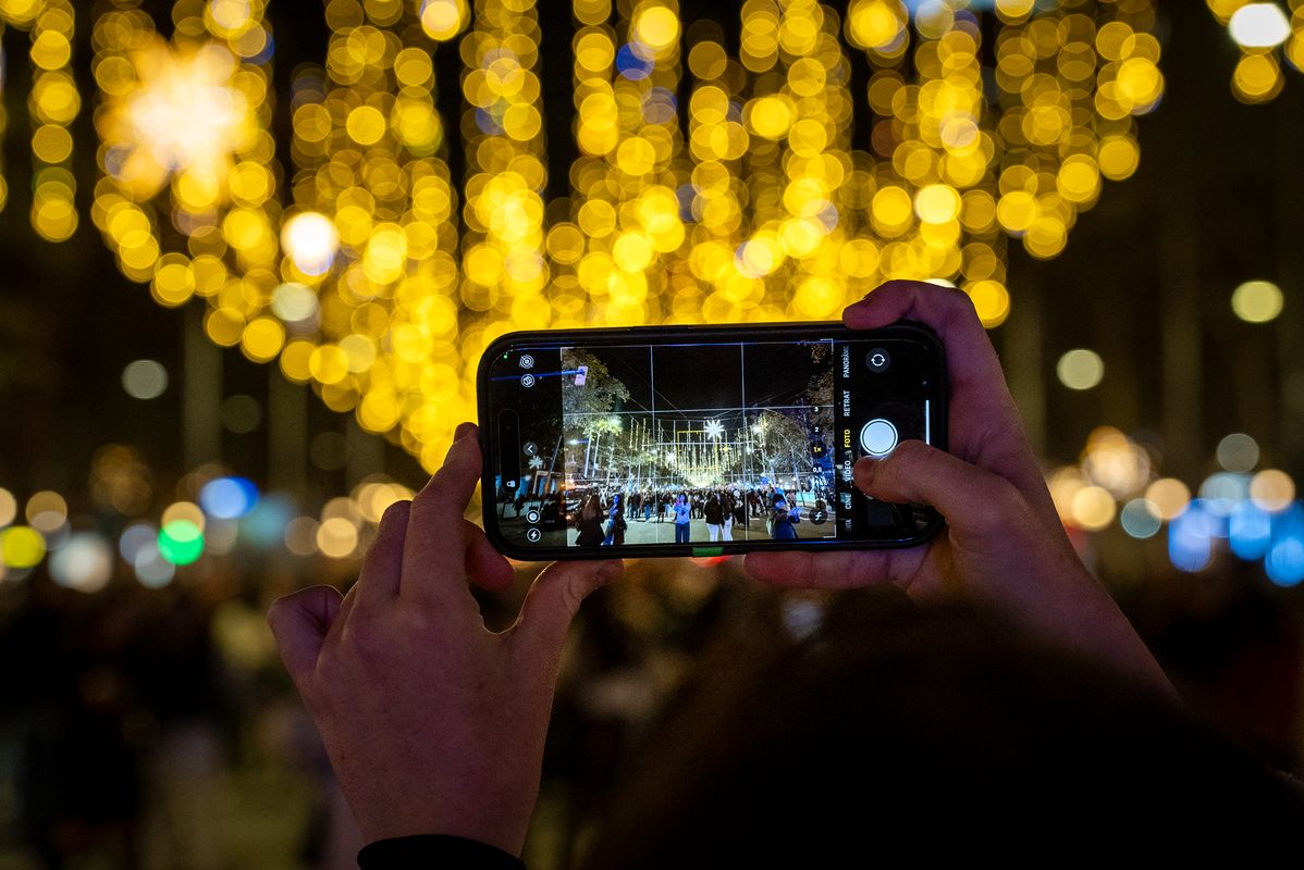 
             Unes mans sostenen un mòbil mentre fotografien els llums de Nadal del passeig...
             Autor: Júlia Arnau
             Mostra els detalls de la imatge Unes mans sostenen un mòbil mentre fotografien els llums de Nadal del passeig...
             