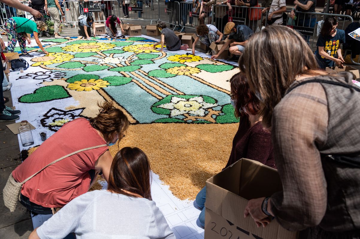 
             Gent de totes les edats treballa amb flors, terra i encenalls en l