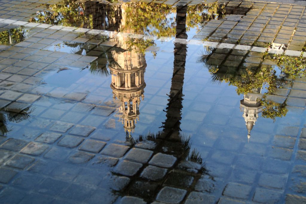 Torres del edificio de Correos y Telégrafos reflejadas en un charco de agua.