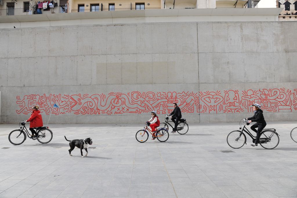 Mural contra el sida de Keith Haring. Ciclistas pasando por delante del mural