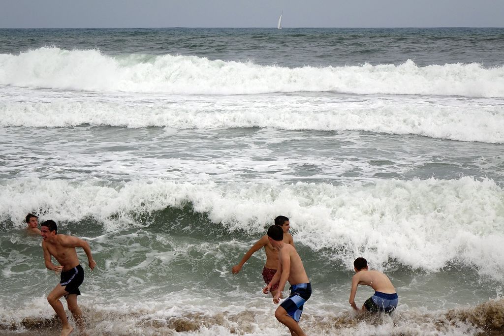 Platja de la Barceloneta. Joves jugant amb les onades