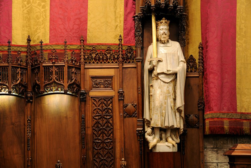 Saló de Cent. Cadirat al costat de l'estàtua de Jaume I de Manel Fuxà amb les parets cobertes de tapissos amb la senyera