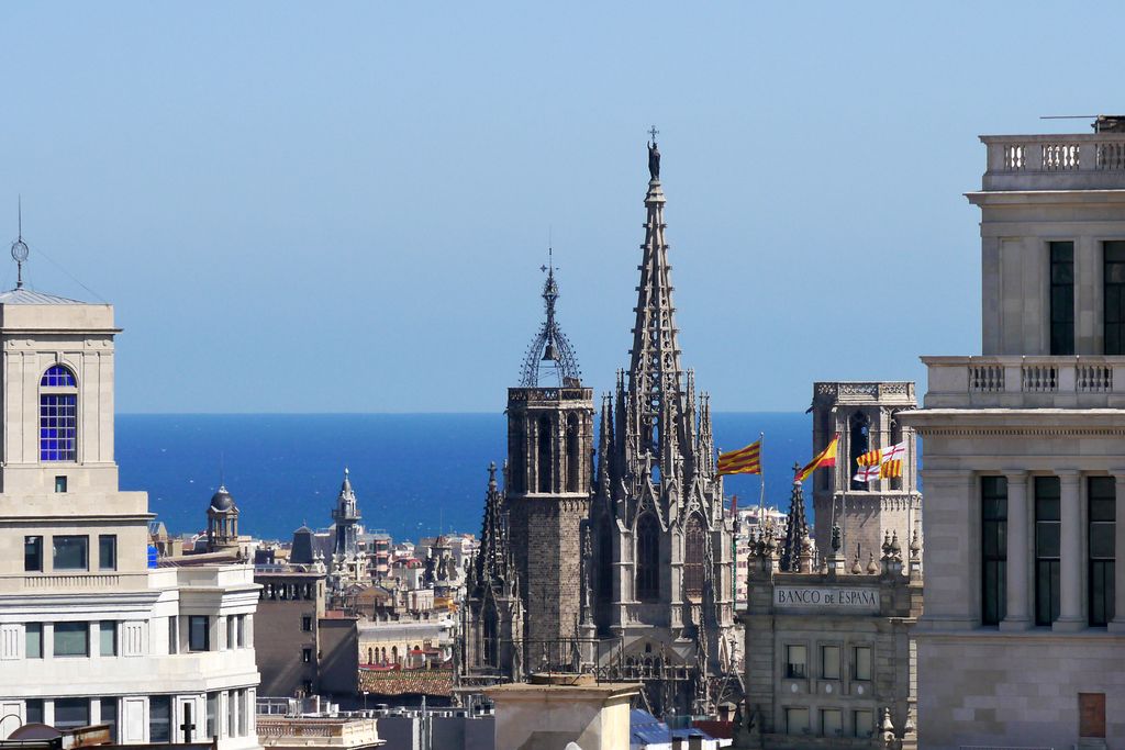 Torres de la Catedral de Barcelona i d'altres edificis del voltant i, al fons, el mar