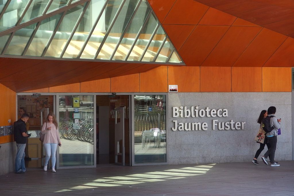 Biblioteca Jaume Fuster.  Porta d'entrada amb usuaris sortint