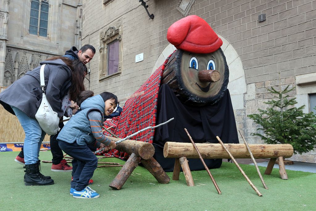 Família fent cagar el tió gegant de la Fira de Santa Llúcia