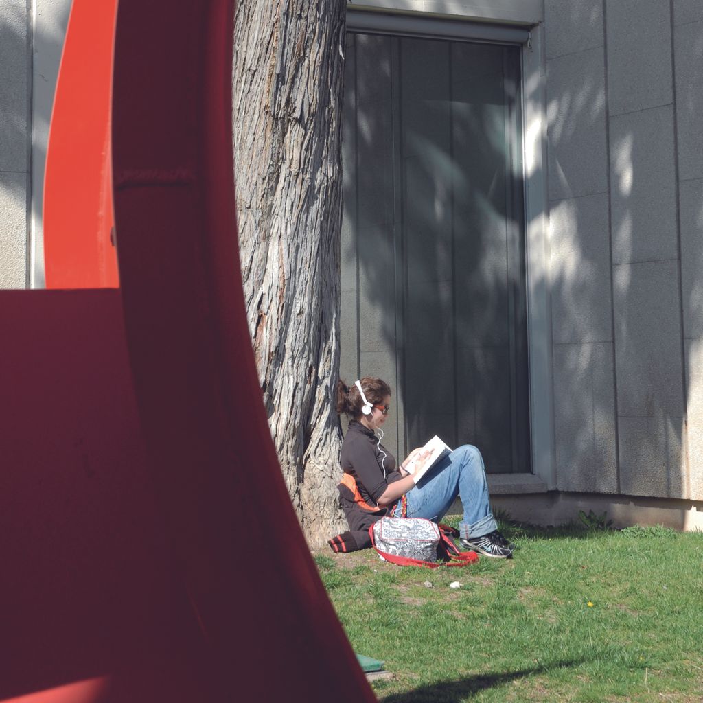 Fundació Joan Miró. Visitant llegint al jardí al costat de l'escultura 4 ales