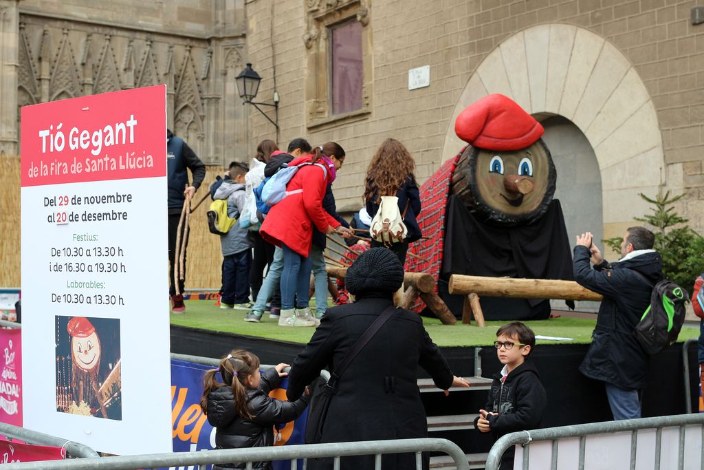 Família fent cagar el tió gegant de la Fira de Santa Llúcia