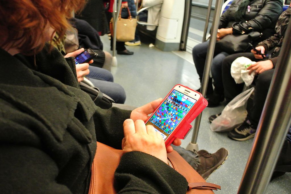 Telèfon mòbil al metro. Dona jugant al Candy Crush