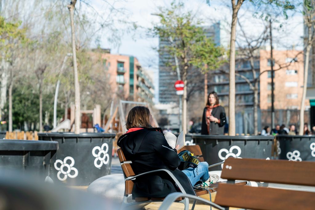 Dona asseguda en un banc llegint un llibre