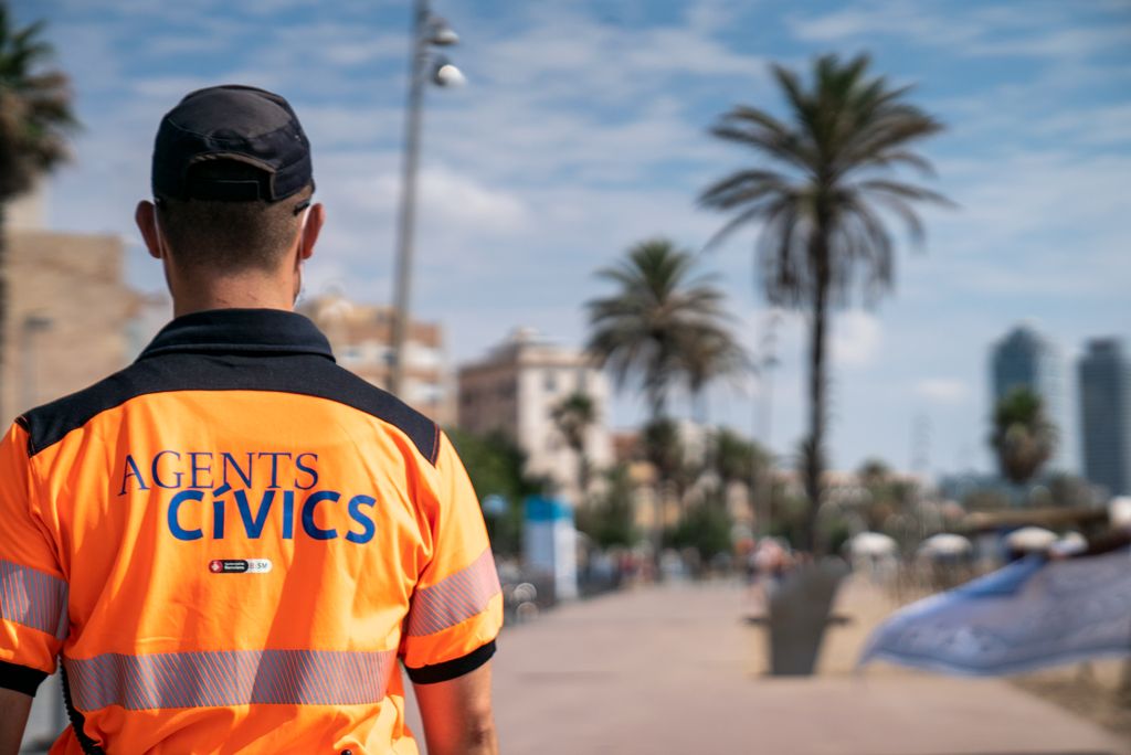 Un agent cívic de l'Ajuntament de Barcelona fa la ronda pel passeig Marítim controlant els accessos i aforaments a les platges