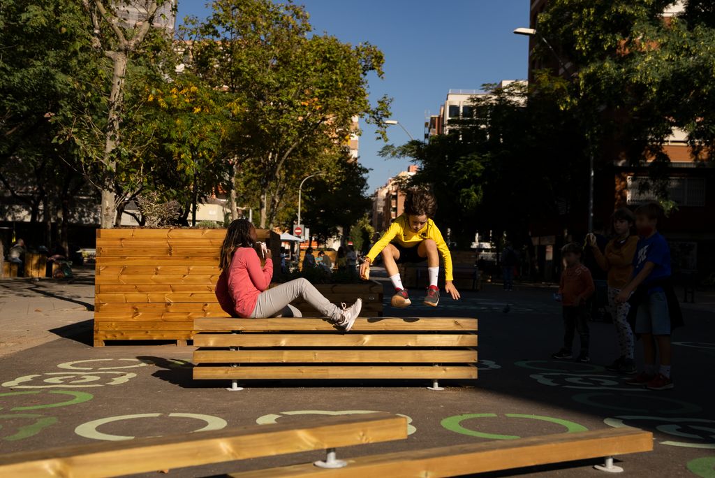 Uns nens juguen enfilant-se als bancs i jardineres instal·lats a la zona pacificada de l'entorn de l'Escola Lavínia