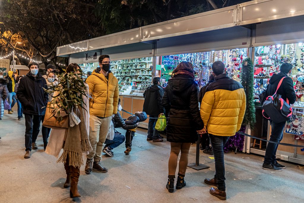 Gent caminant entre les parades de la Fira de Nadal a Sagrada Família, alguns amb alguna compra ja feta i d’altres esperant en alguna parada