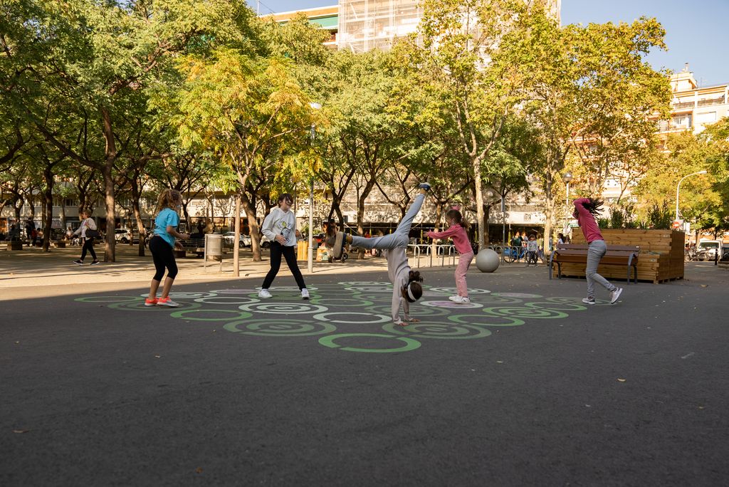 Unes nenes juguen fent tombarelles i corrent al mig de la zona pacificada de l'Escola Lavínia