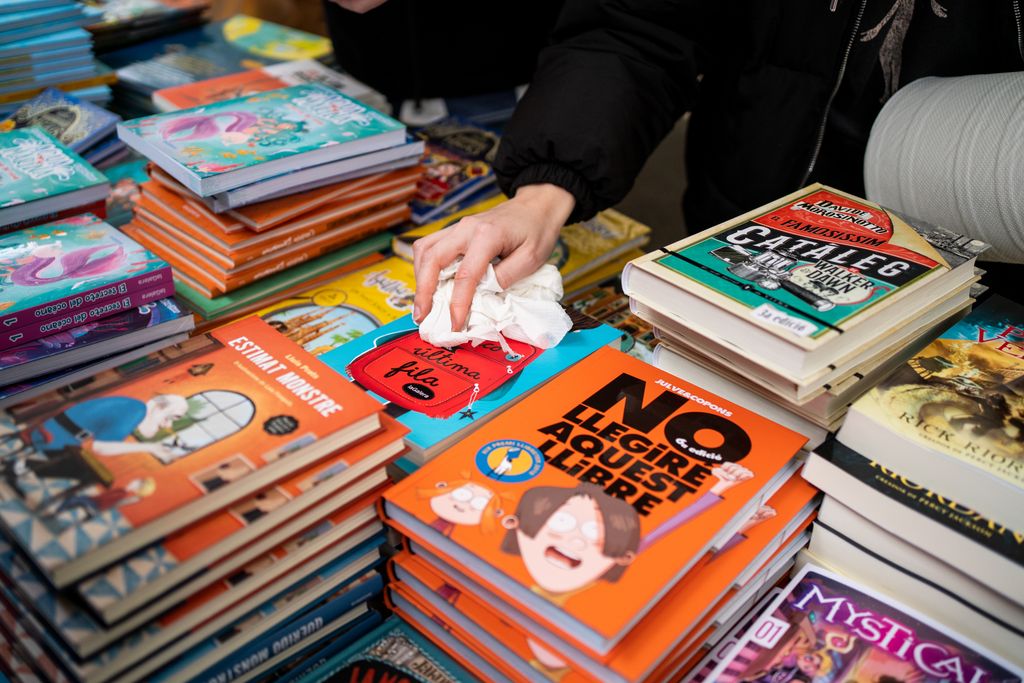 Llibreter eixugant la coberta d’un llibre a una parada de Sant Jordi