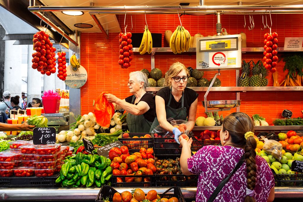 Venedores atenent les clientes a una parada de fruites i verdures del mercat
