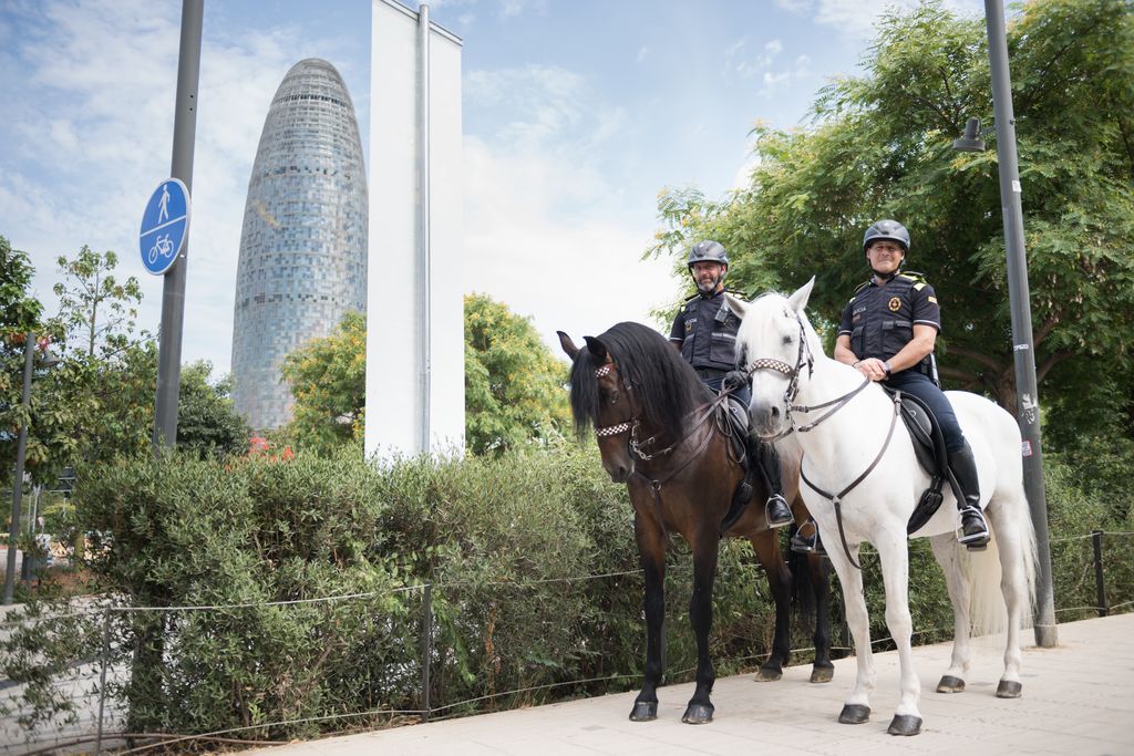 Dos membres de la Guàrdia Urbana muntant a cavall amb la Torre de les Aigües de Glòries a un costat