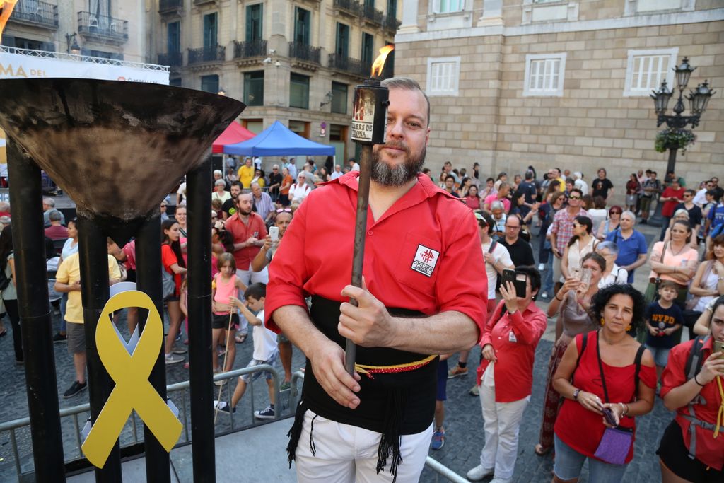 Representant d'una colla castellera recollint en una torxa la flama del Canigó del peveter
