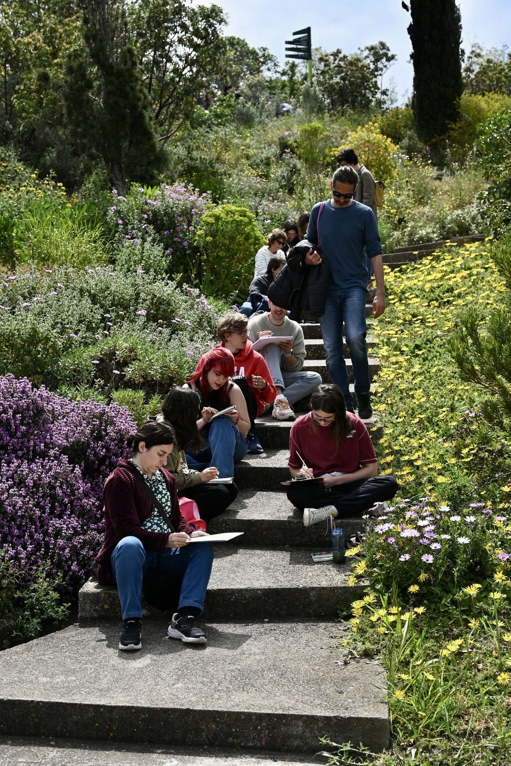 Grup de persones assegudes i pintant al Jardí Botànic amb motiu del 25è aniversari.