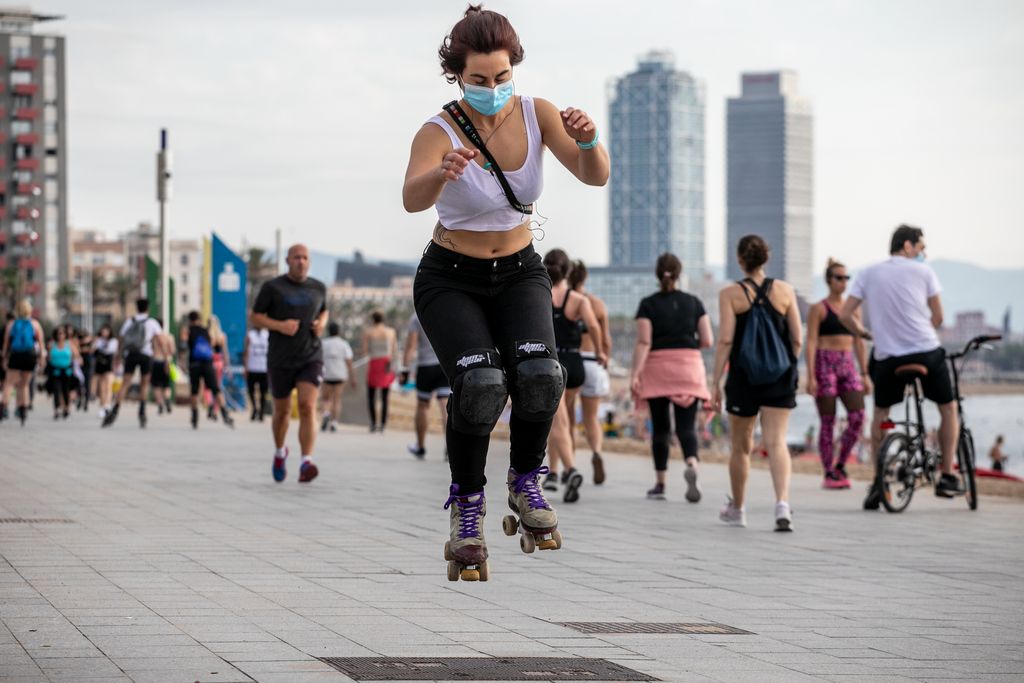 Una patinadora amb mascareta roda pel passeig del Mare Nostrum, al seu voltant hi ha gent caminant i fent esport