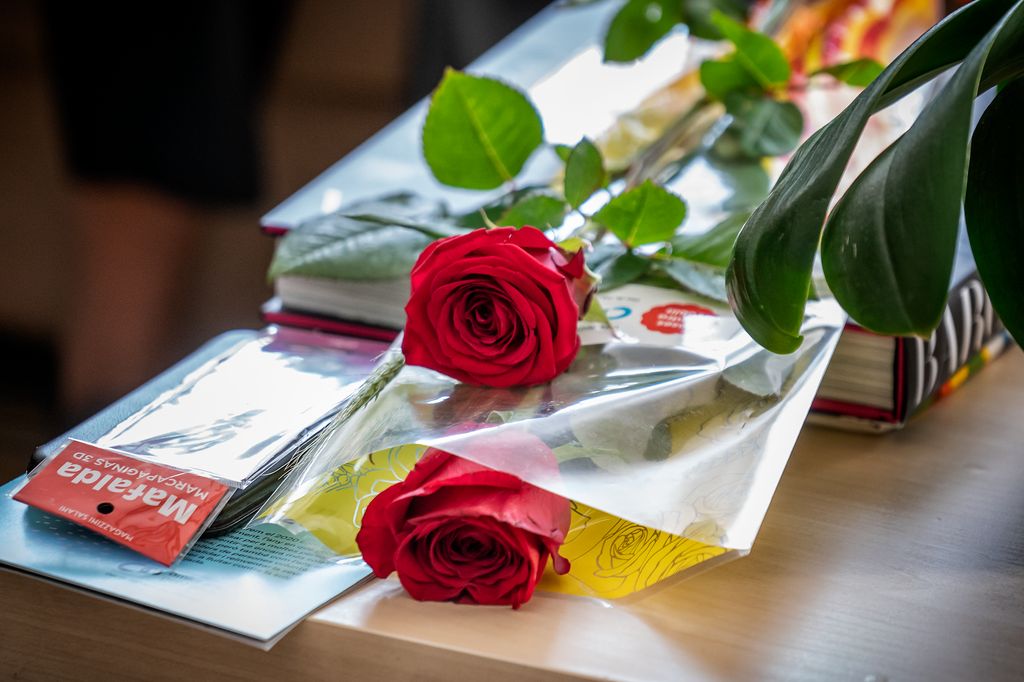 Un par de rosas, un libro y un punto de libro sobre una mesita durante el Día de Sant Jordi