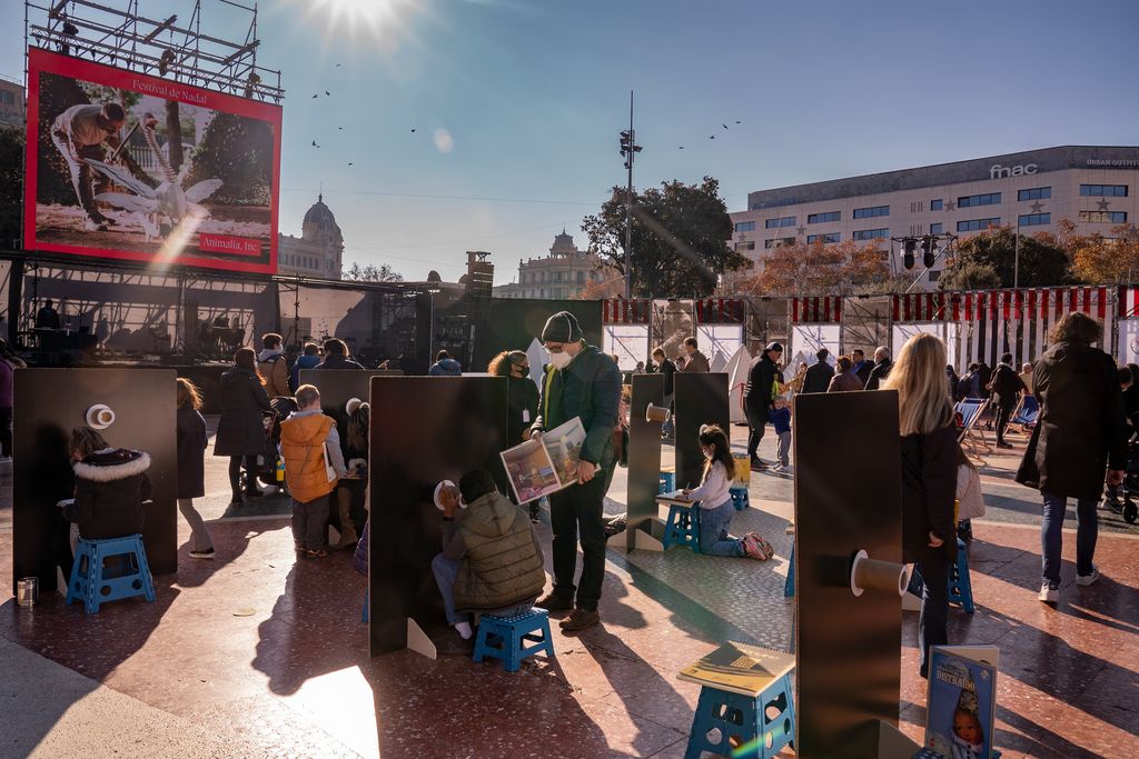 Famílies amb infants participen en un joc del Festival de Nadal que consisteix a explicar un dibuix d'un conte perquè l'altre participant el pinti segons les explicacions