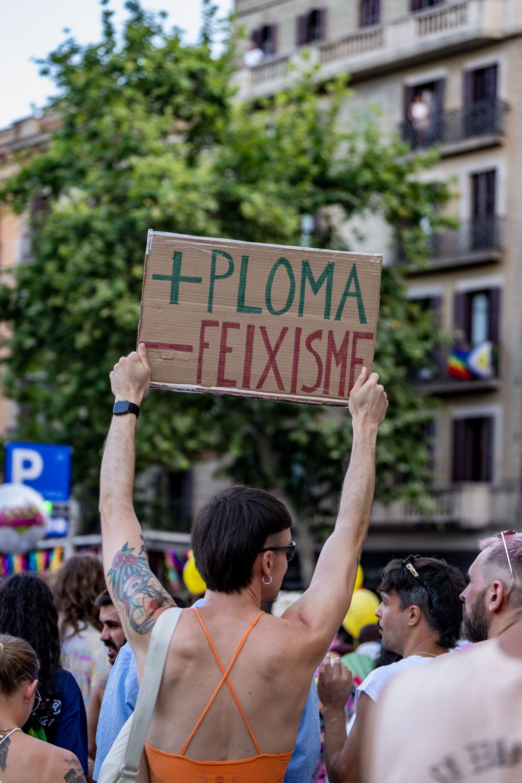 Una persona, vista de espaldas, enseñando un cartel en la manifestación del Pride Barcelona 2025 que dice: + pluma, - fascismo 
