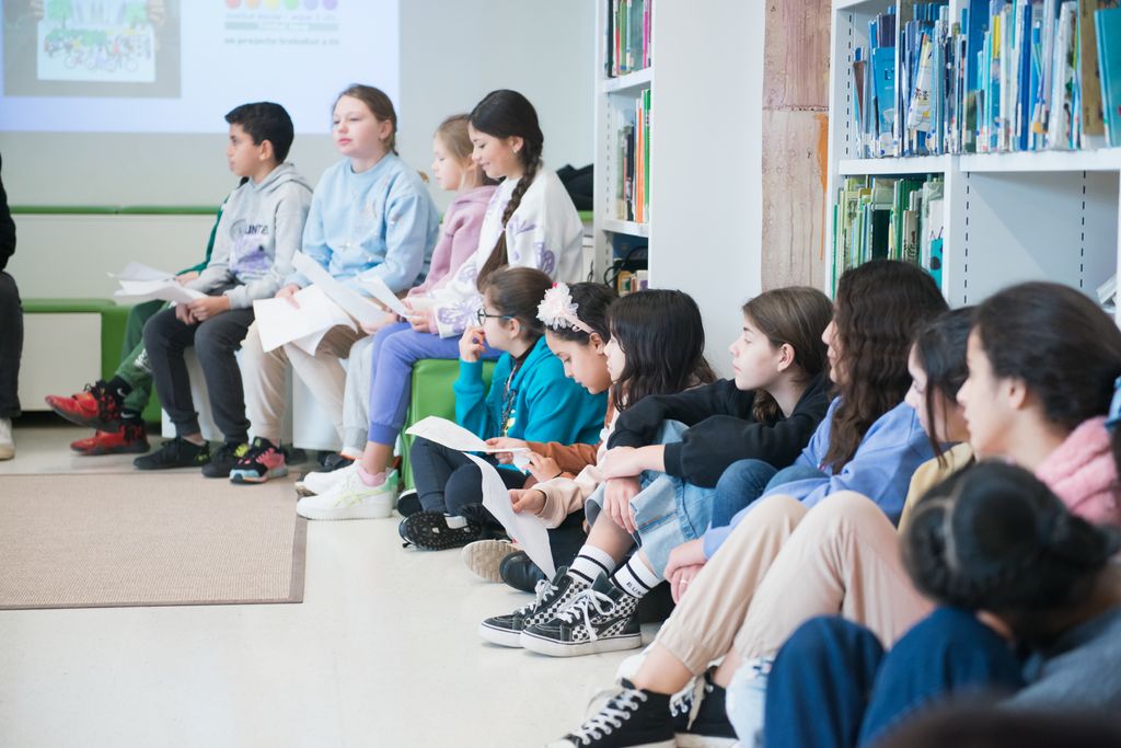 Alumnes de l'Institut Escola Trinitat Nova asseguts a terra i en un banc durant l’activitat “Barcelona, la meva ciutat”.
