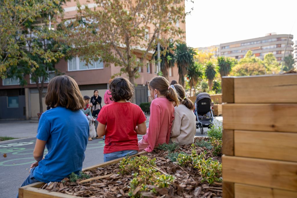 Unos niños y niñas conversan apoyados en una de las jardineras instaladas en la zona pacificada del entorno de la Escuela Lavínia