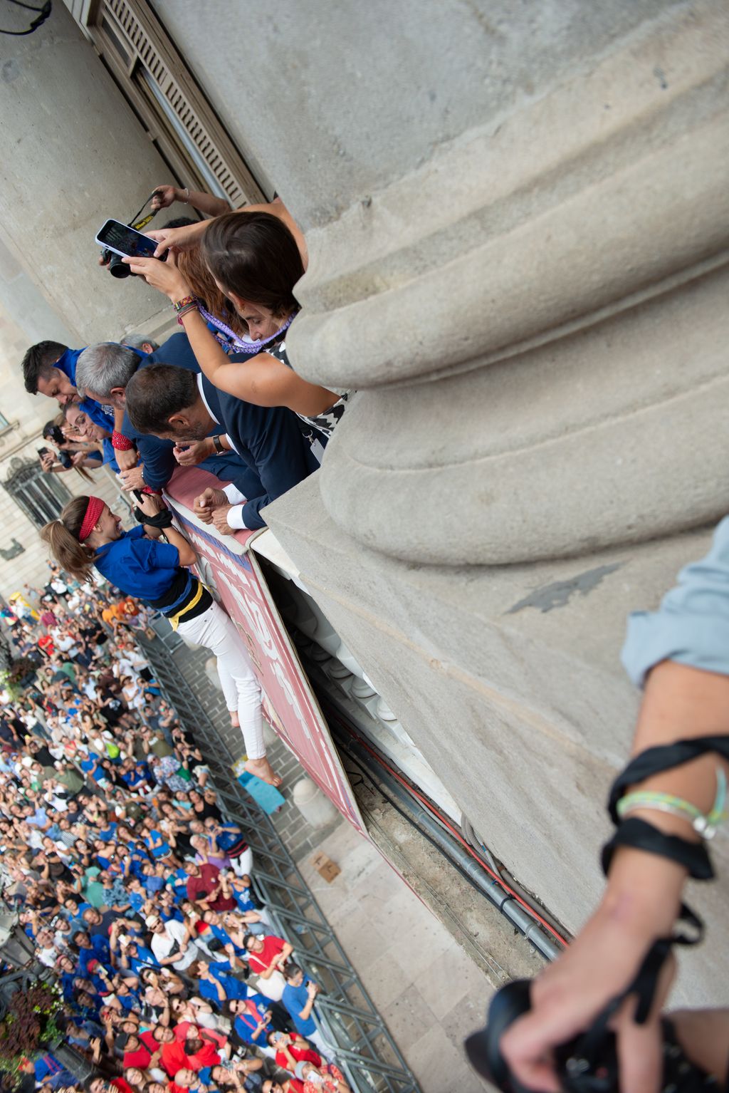 Un membre dels Castellers de la Vila de Gràcia eleva una de les seves companyes des del pilar al balcó de l’Ajuntament durant la Diada Castellera de la Mercè.