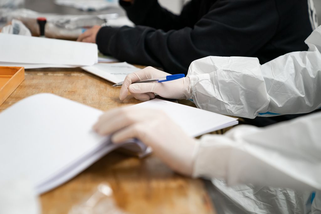 Els membres de les meses electorals, vestits amb l'equip de protecció individual, registren els votants