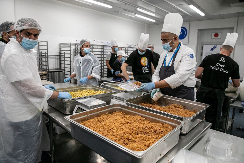 Cuiners i voluntaris pesen les racions i omplen els envasos