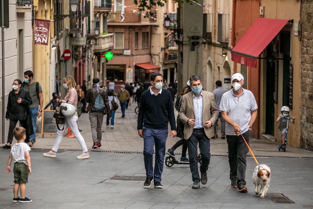 Un grup d'homes conversa mentre passegen el gos pel carrer Major de Sarrià