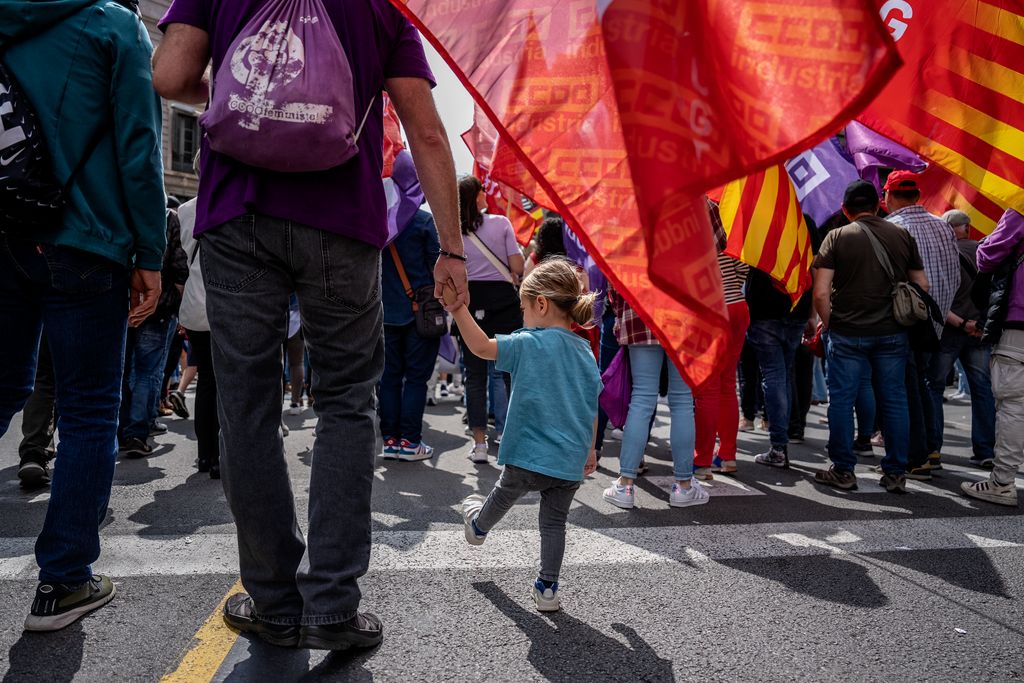 Una nena petita dona la mà a un adult enmig de la multitud durant la manifestació celebrada l’1 de maig amb motiu del Dia del Treballador.