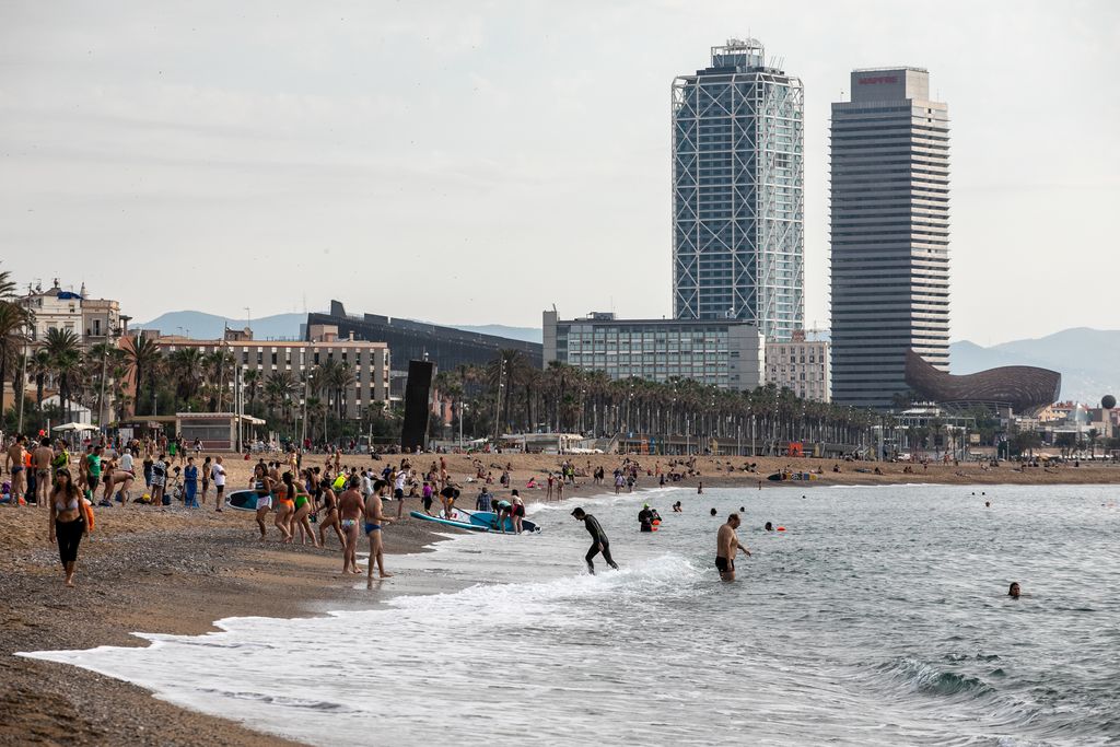 Gent banyant-se, caminant i gaudint de la platja de Sant Sebastià