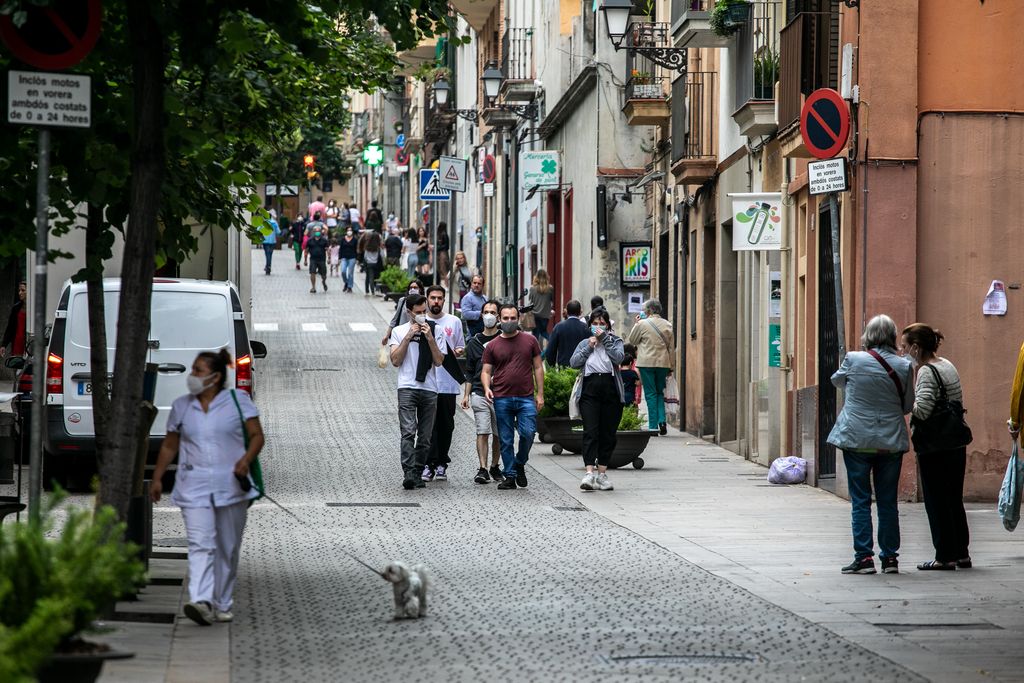 Grups de gent passegen i van de compres pel carrer Major de Sarrià