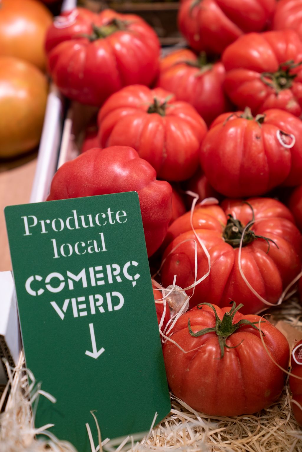 Tomàquets a una parada amb el rètol de “Producte local / Comerç verd”