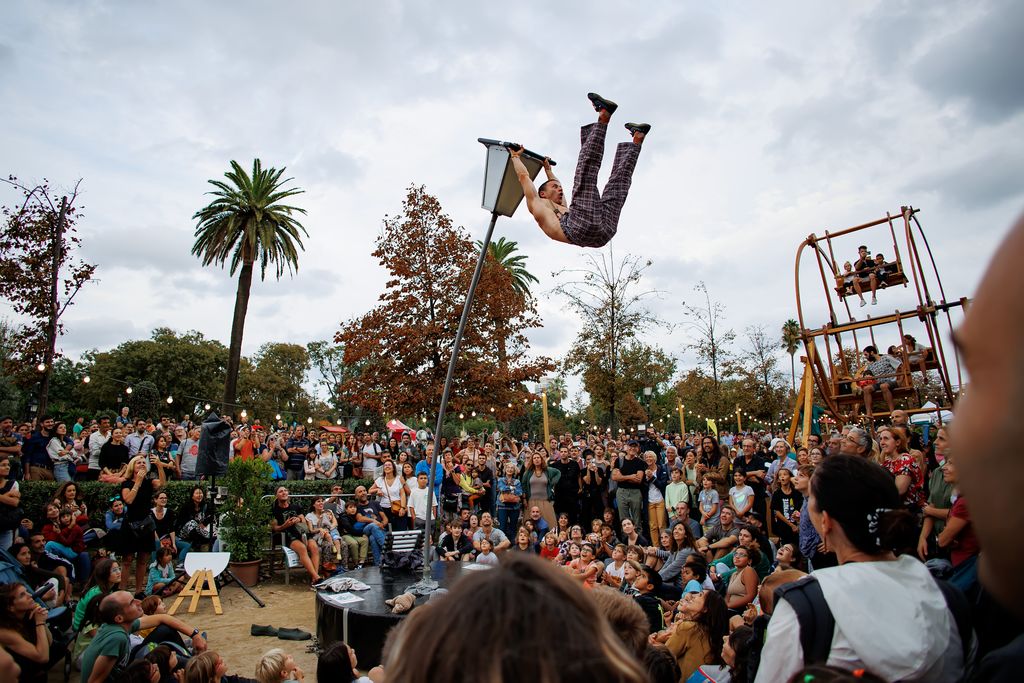 Gent gaudint de l’espectacle “Noah: Sway Pole (Drunken Master)” dins del MAC Festival al parc de la Ciutadella, en la qual un dels artistes apareix fent acrobàcies penjat d’un fanal