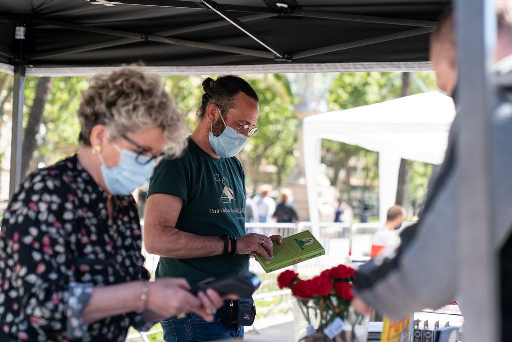 Uns llibreters atenen els clients en una de les parades instal·lades al passeig de Lluís Companys amb motiu de la diada de Sant Jordi.