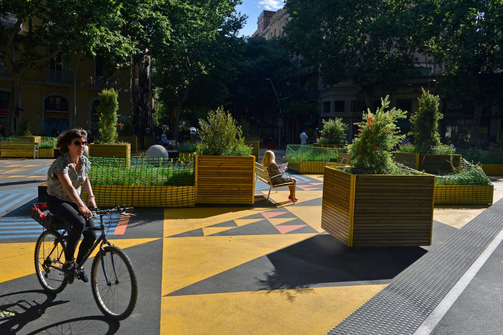 Cruïlla del carrer del Comte Borrell amb Parlament, a la superilla de Sant Antoni, on es troba situada una zona de lleure i jocs infantils delimitada per jardineres i senyalització horitzontal. Una ciclista la creua i hi ha una dona llegint en un banc