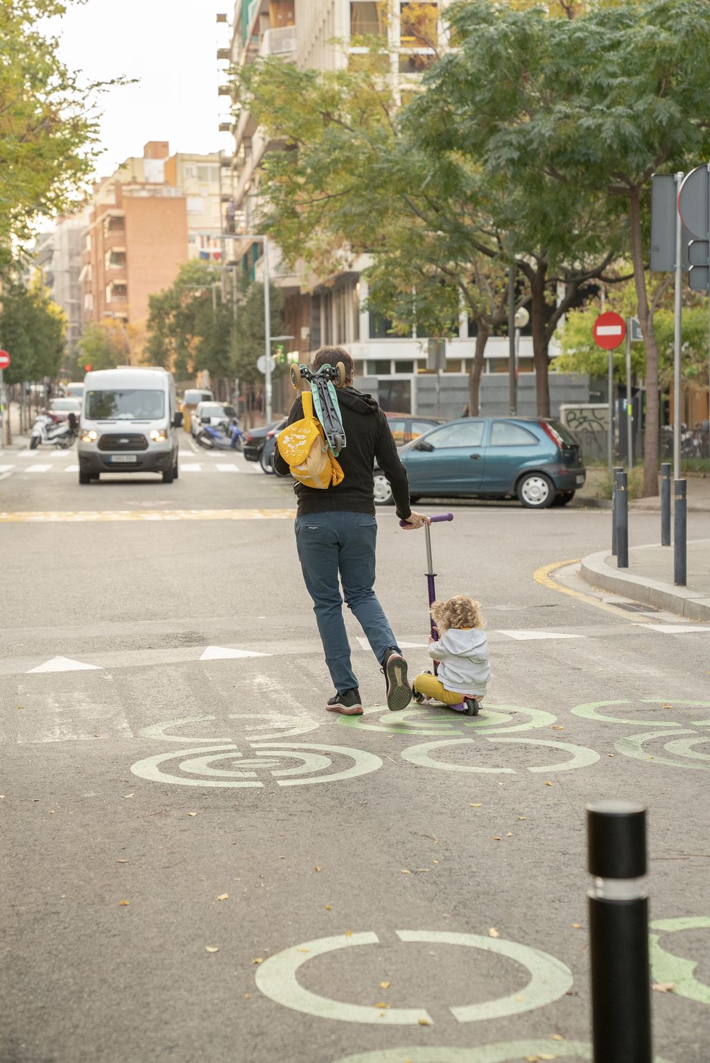 Un pare arrossega al seu infant en patinet per la zona pacificada davant de l'Escola Lavínia