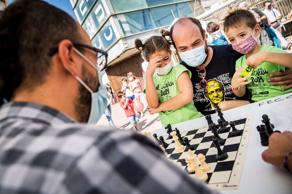 Un pare amb els fills juga a escacs amb un adversari durant les activitats organitzades a la Festa de l'Associa't al Centre Cívic de la Farinera del Clot