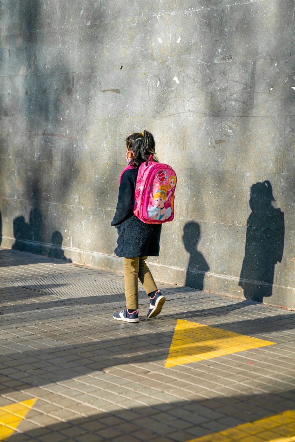 Un infant va camí de l’escola per una vorera on hi ha els panots pintats de groc