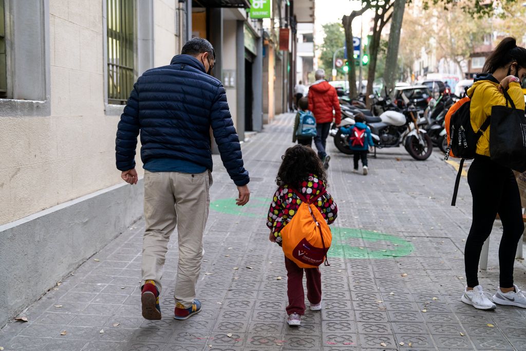 Un pare amb la seva filla caminen per l’entorn pacificat de l’Escola Marillac. Es veu el paviment amb dibuixos de color verd que senyalitzen la zona