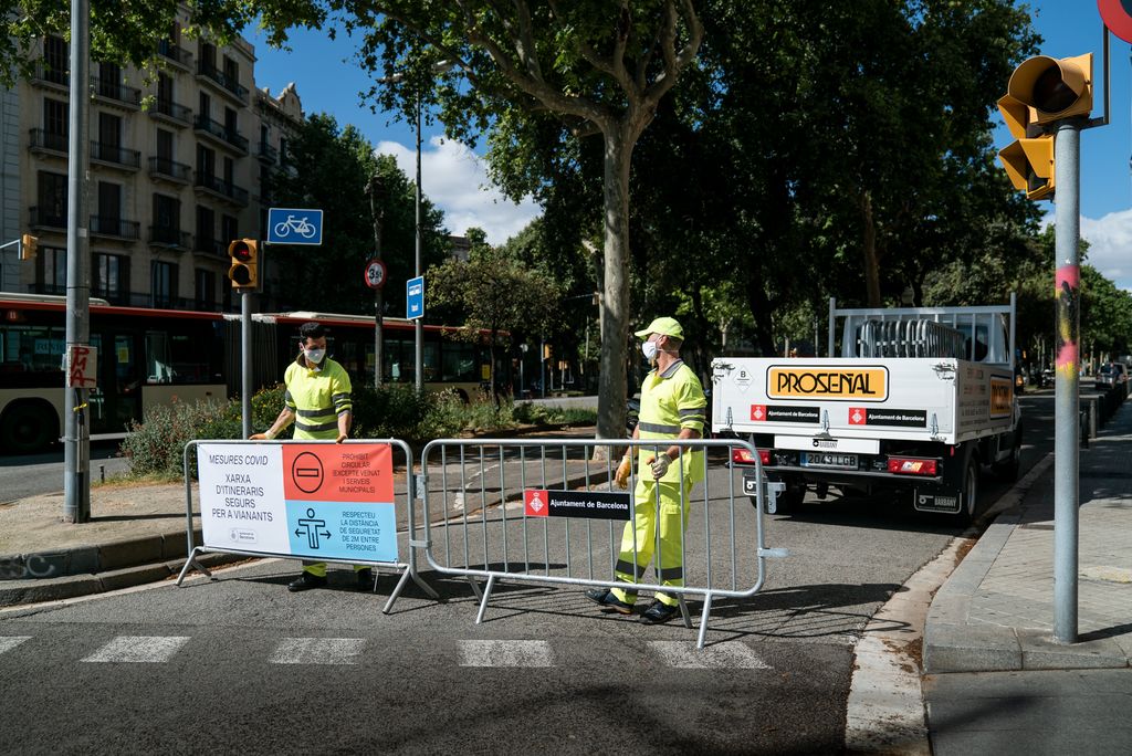 Dos treballadors col·loquen les tanques al lateral de l'avinguda Diagonal a prop del passeig de Sant Joan per crear una xarxa d'itineraris segurs per a vianants