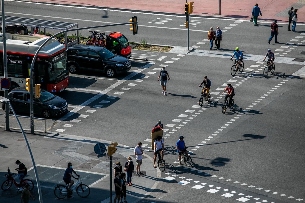 Persones i bicicletes travessant el pas de vianants de l'avinguda del Paral·lel amb la plaça d'Espanya